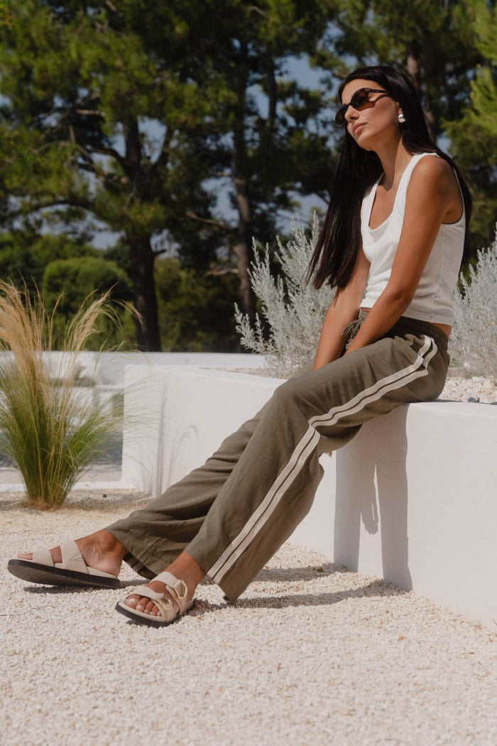 Woman wearing khaki wide-leg drawstring pants with an elastic waist, featuring a relaxed fit and side stripe detail, styled with a plain white tee