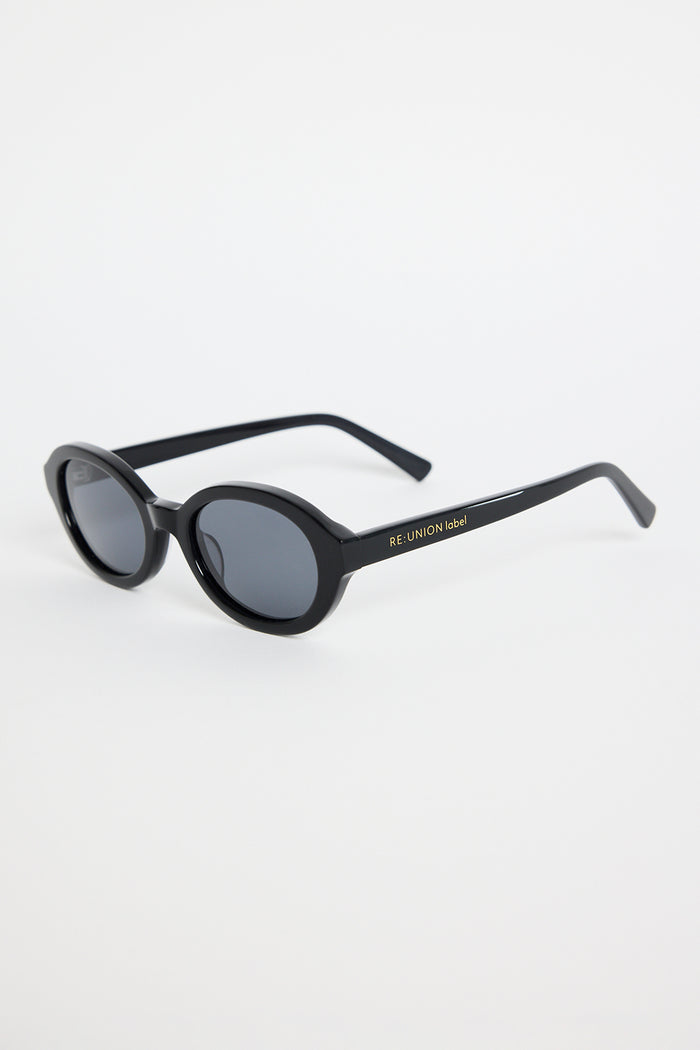 Black oval sunglasses with dark tinted lenses and a glossy frame, photographed against a white background