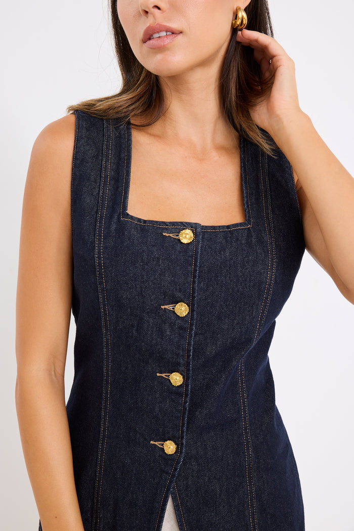 model wears a dark blue denim vest with a beige linen midi skirt