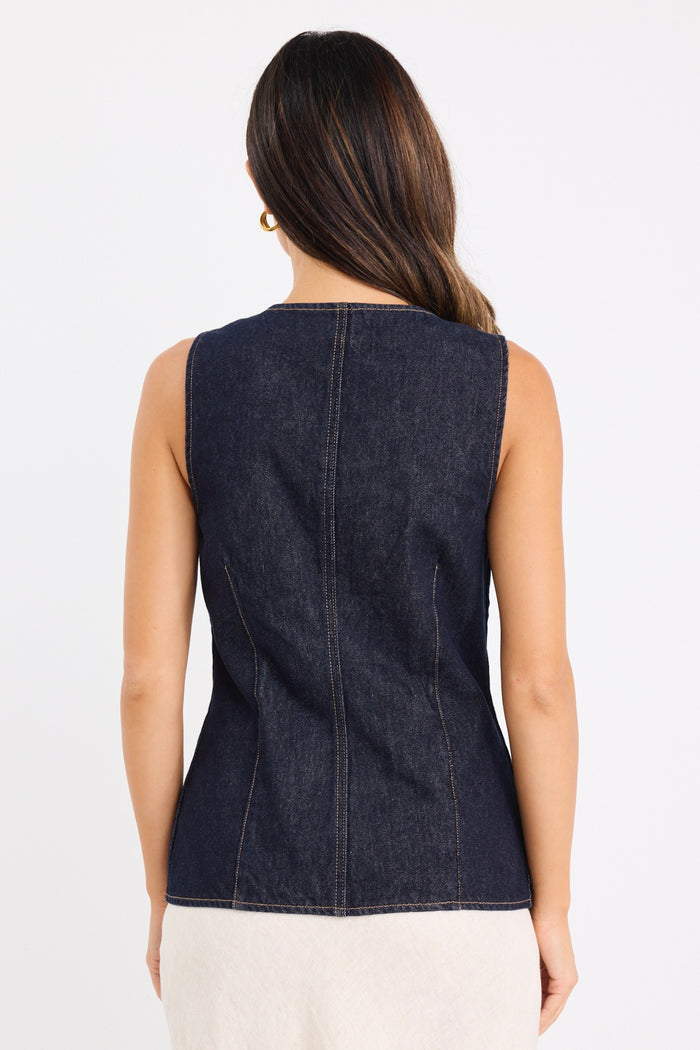 model wears a dark blue denim vest with a beige linen midi skirt