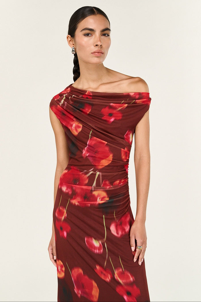 Woman wearing a red floral off-shoulder dress against a white background