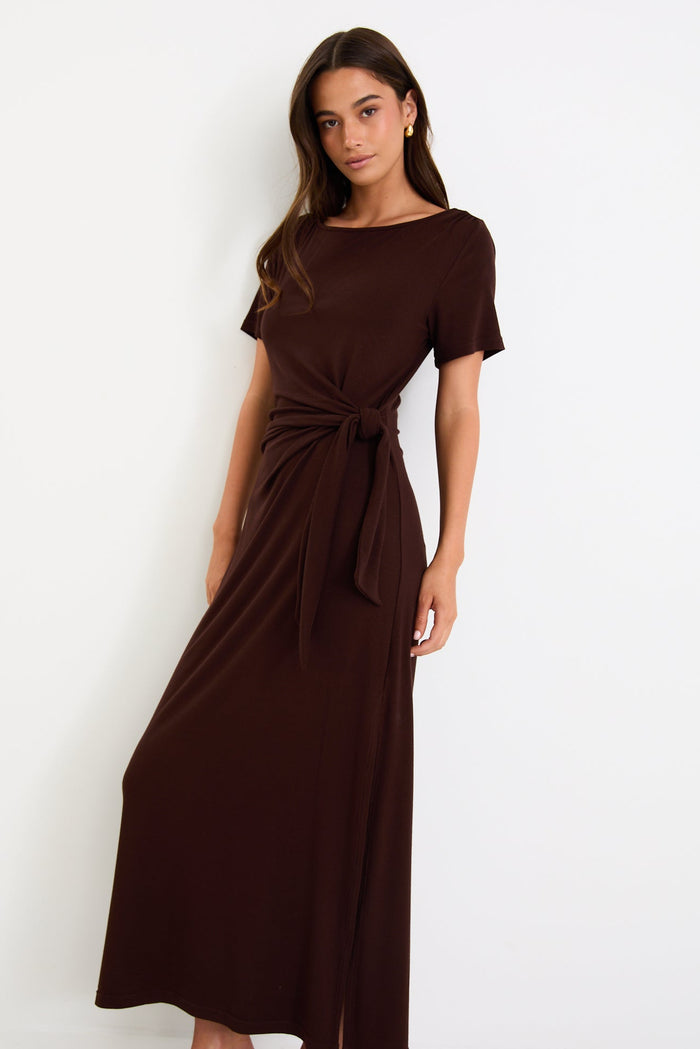 Woman wearing a brown dress with a knot detail on a white background