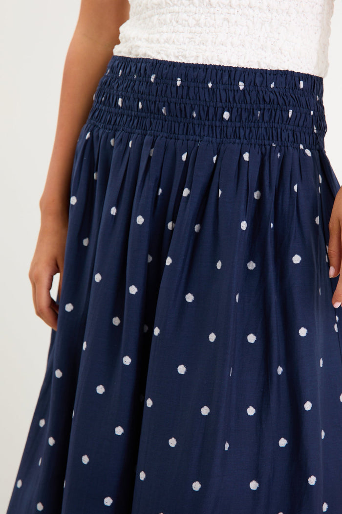 Model wearing a navy polka dot maxi skirt with a shirred elastic waist and a flowy silhouette.