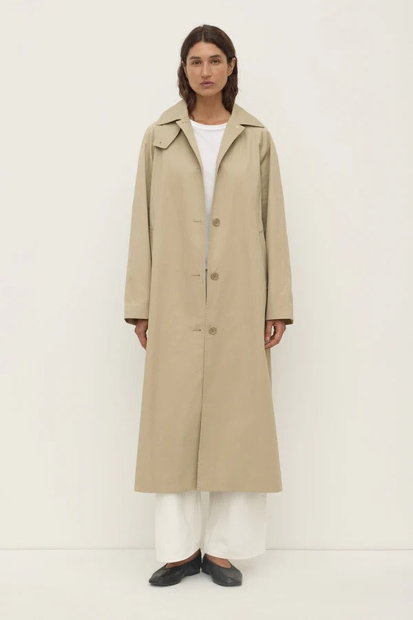 Person wearing a beige trench coat on a white background