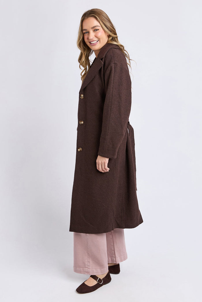 Woman wearing a long brown coat on a white background