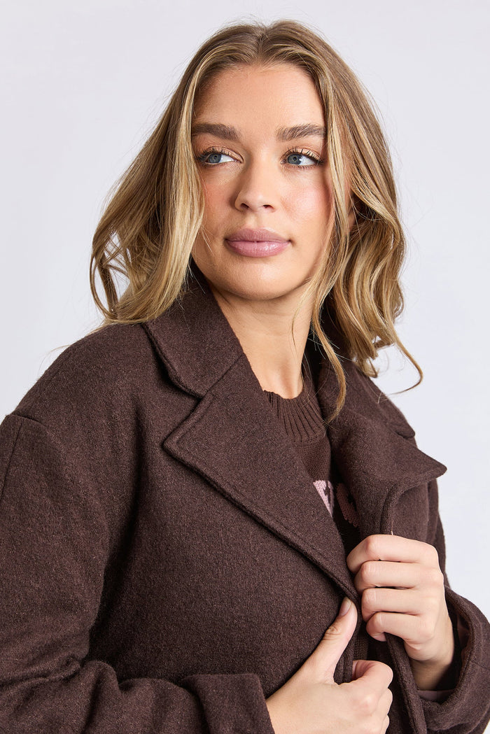 Woman wearing a brown coat against a plain background