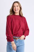 Woman wearing a red blouse and light blue jeans on a white background