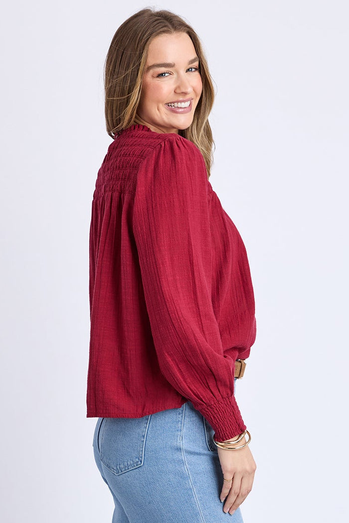 Woman wearing a red blouse and blue jeans on a white background