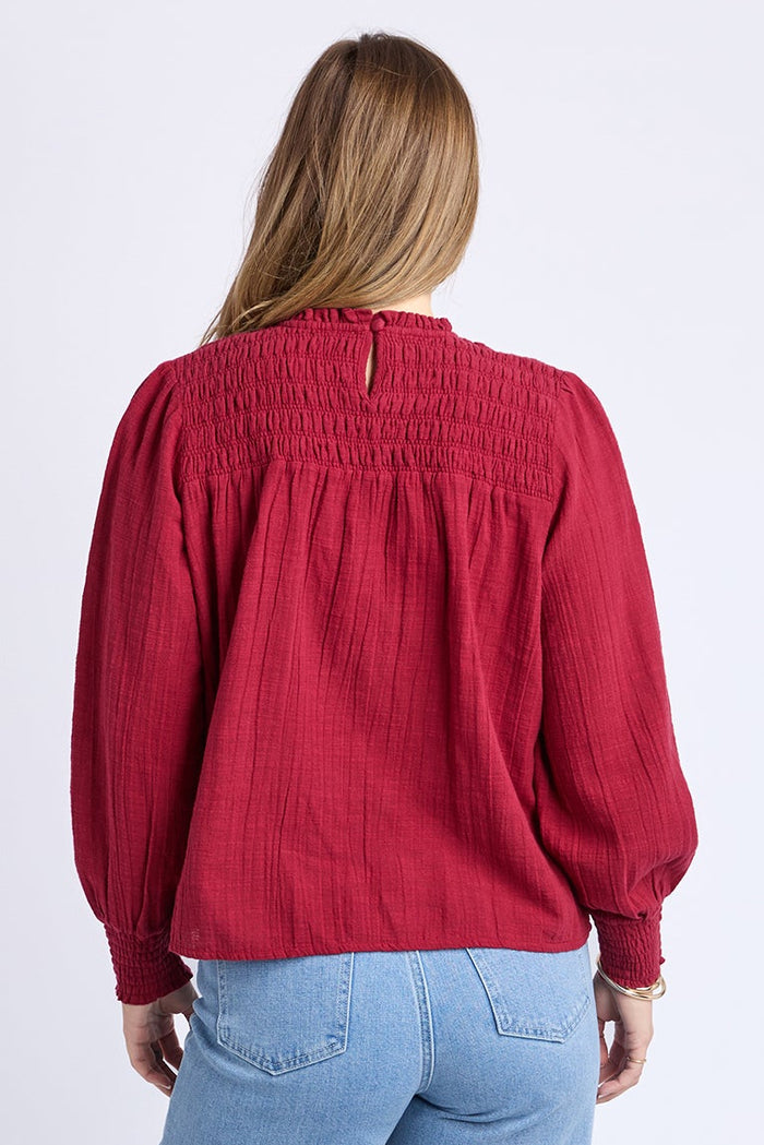 Person wearing a red blouse and blue jeans on a white background