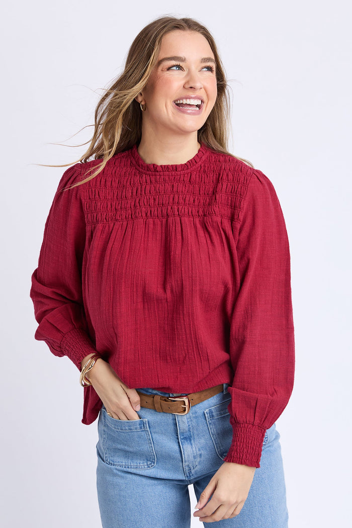 Woman wearing a red blouse and blue jeans on a white background