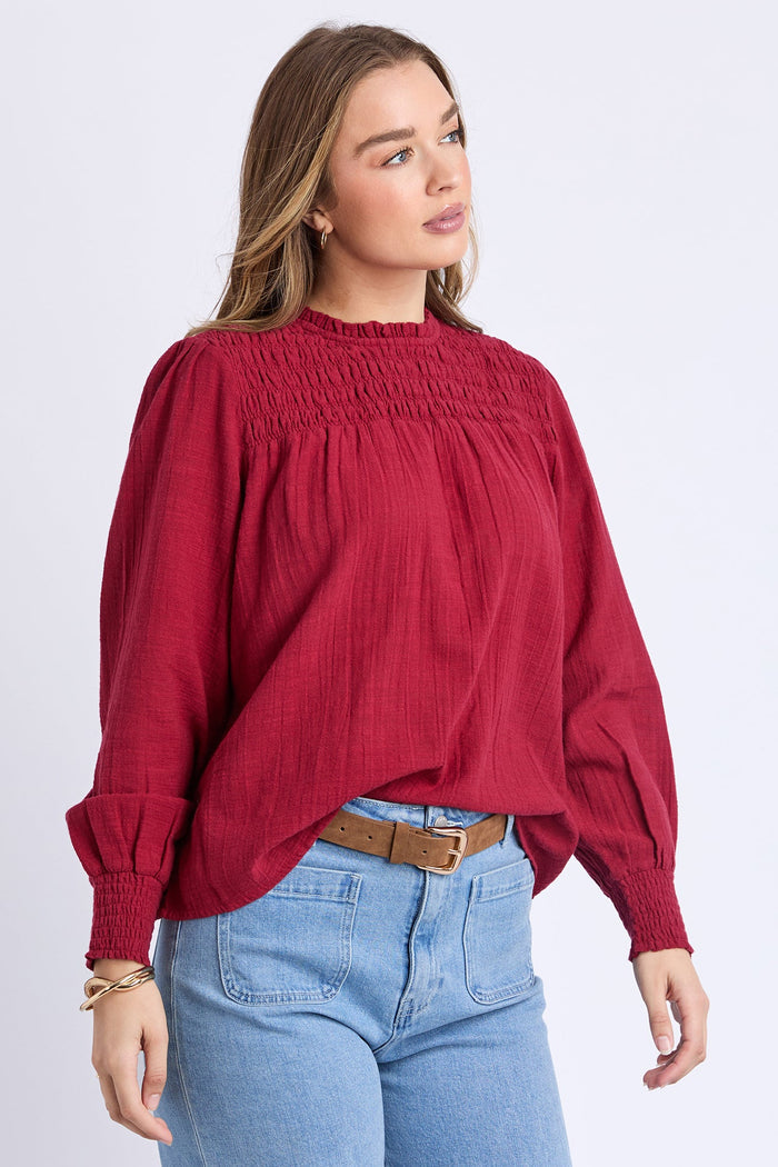 Woman wearing a red blouse and blue jeans on a white background
