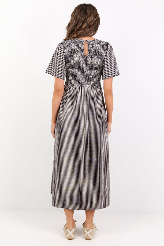 Woman wearing a gray checkered dress on a white background