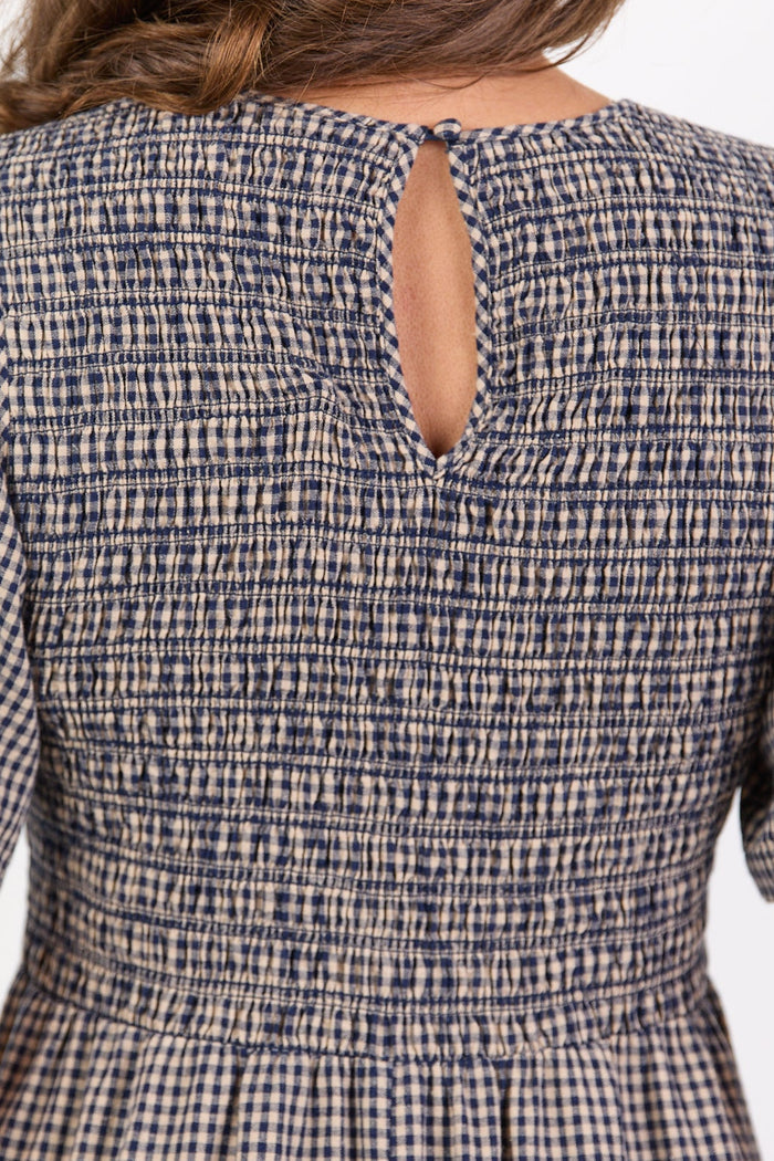 Woman wearing a checkered dress with a cut-out back detail on a white background
