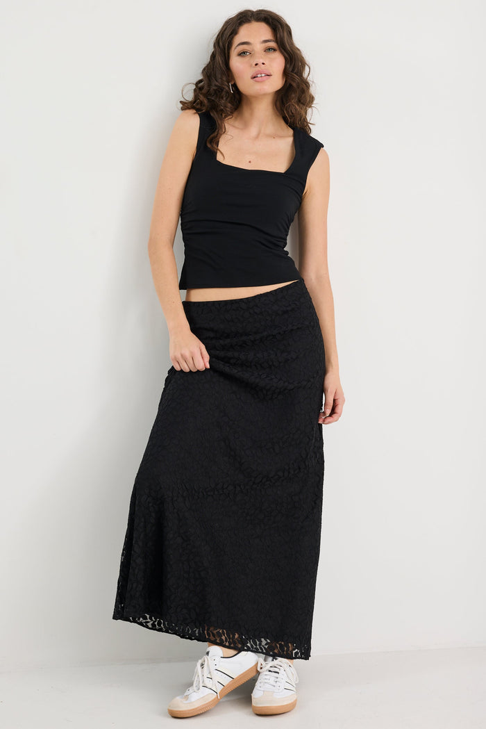 Woman wearing a black sleeveless top and long skirt on a white background