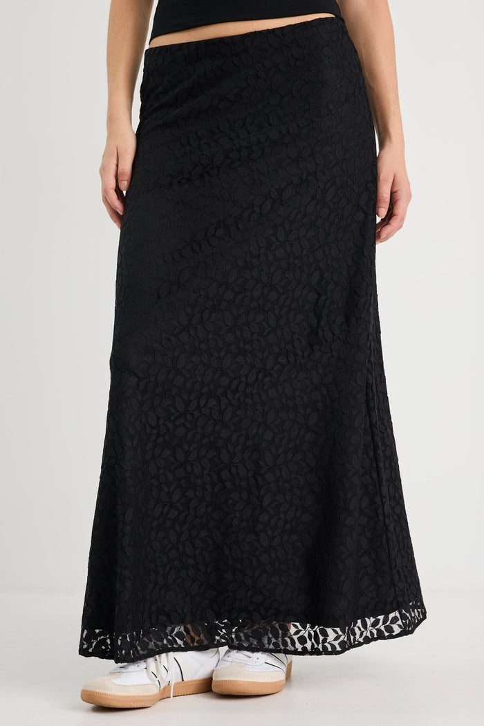 Person wearing a black lace-trimmed skirt on a plain background
