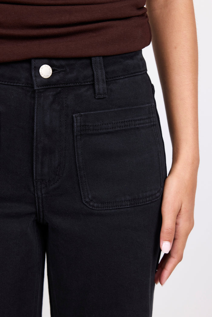 Black pants with a white button on a plain background