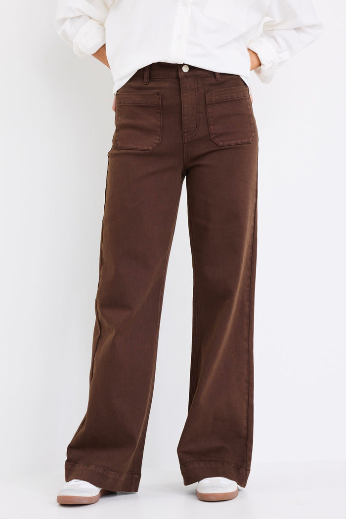 model wears a brown wide jean with a white linen blouse