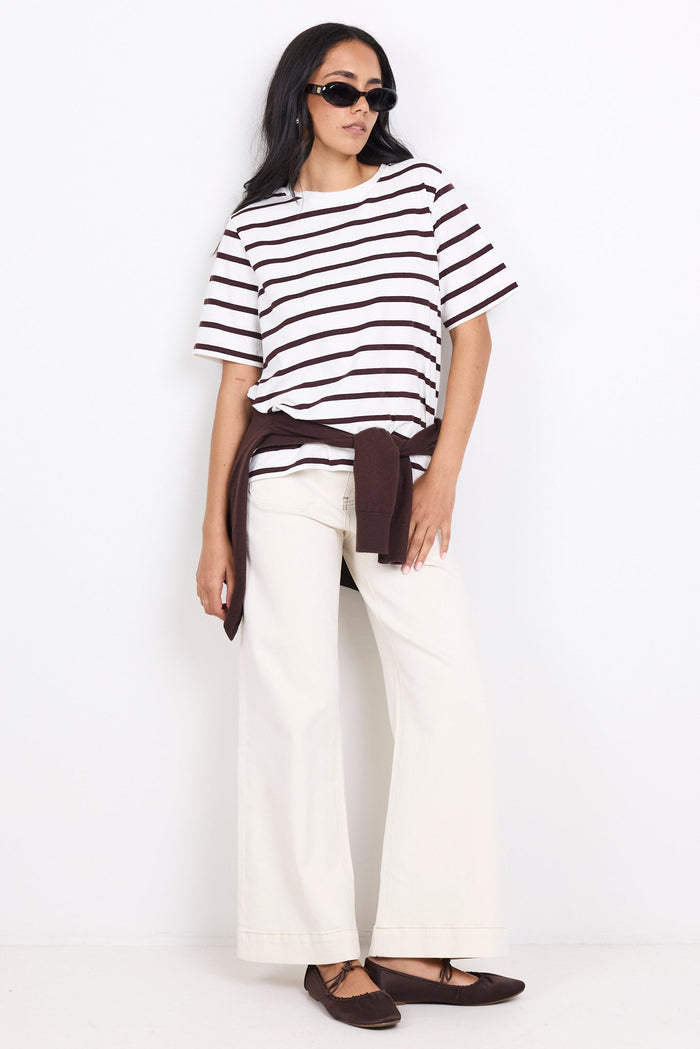Woman wearing a black and white striped shirt with white pants on a white background