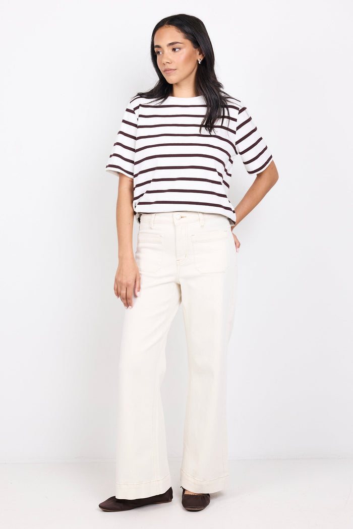 Woman wearing a black and white striped shirt and white pants on a white background