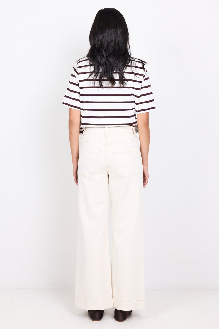 Person wearing a black and white striped shirt and white pants on a white background