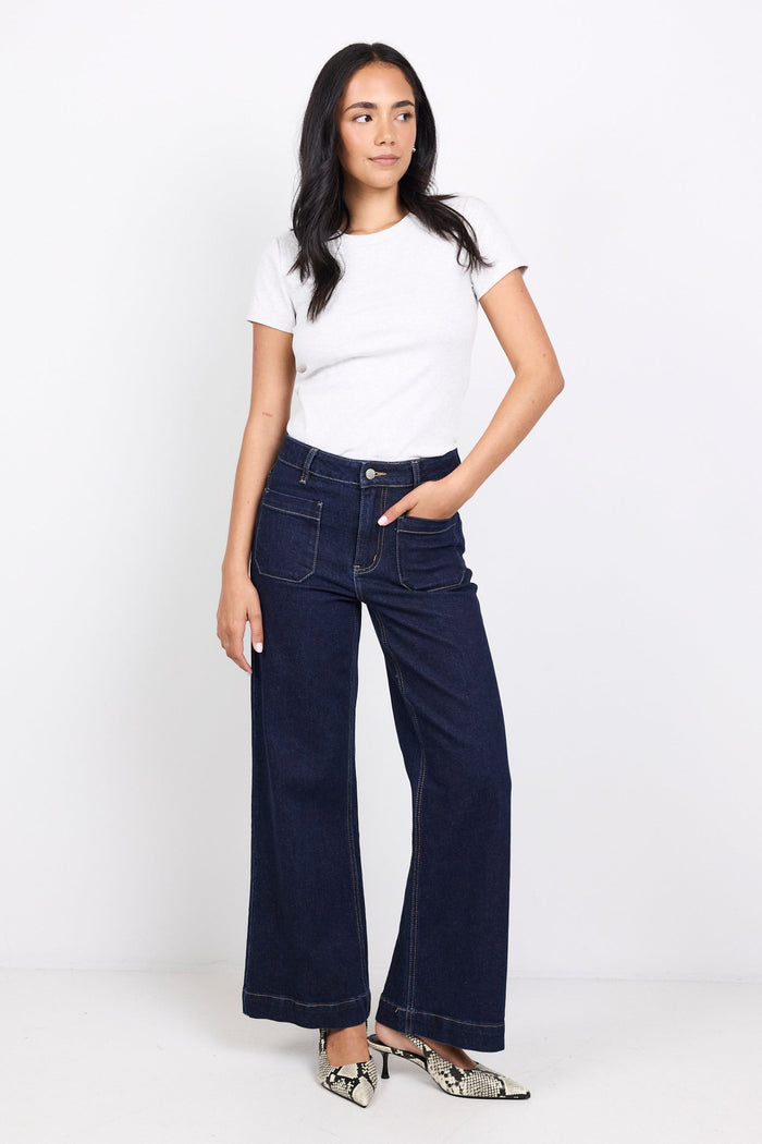 Woman wearing a white t-shirt and dark blue jeans on a white background