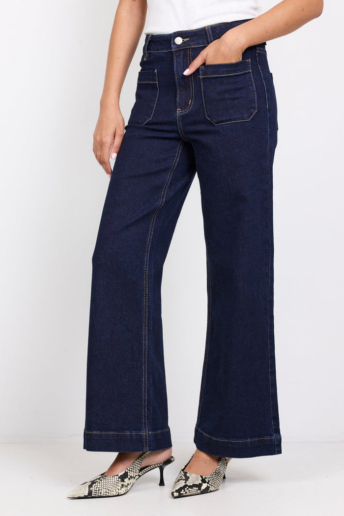 Person wearing dark blue jeans and a white top on a white background