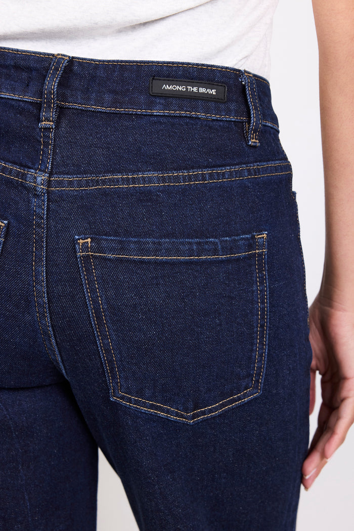 Close-up of dark blue jeans with a brand label on a white background