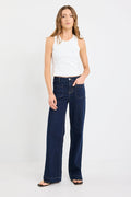Woman wearing a white top and dark blue jeans on a white background