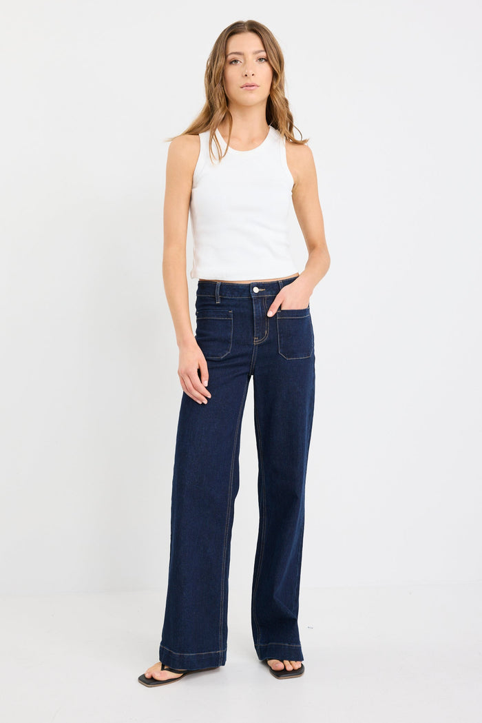 Woman wearing a white top and dark blue jeans on a white background