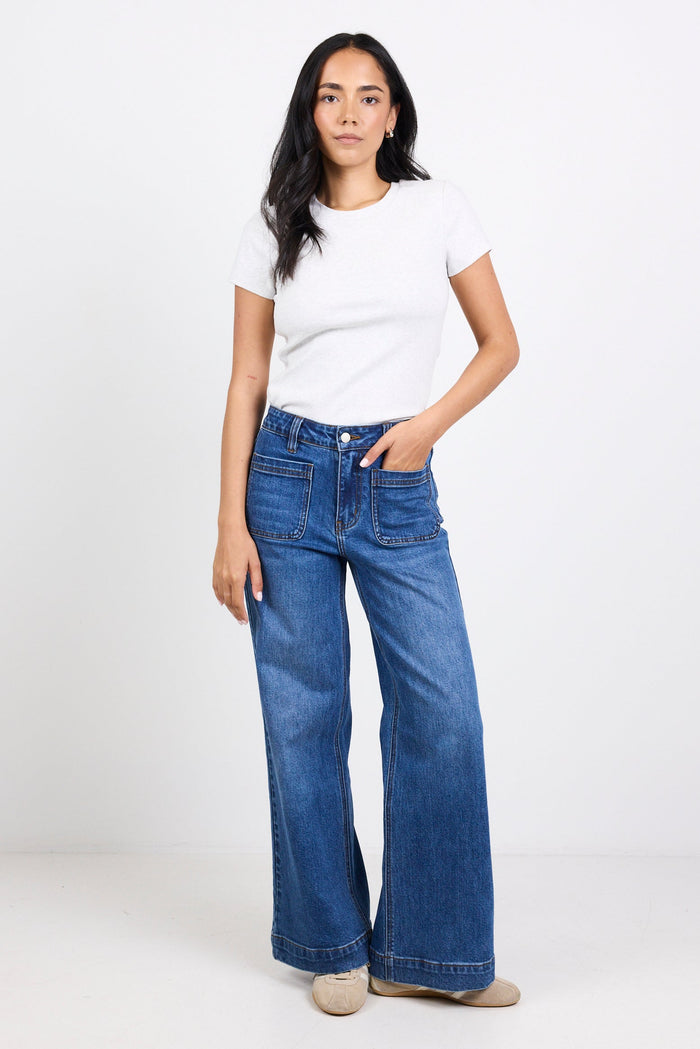 Woman wearing blue jeans and a white t-shirt on a white background