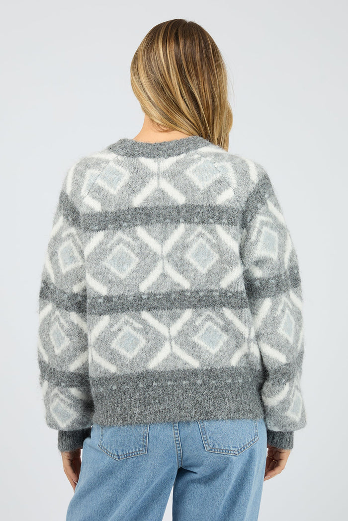Person wearing a gray and white patterned sweater on a plain background