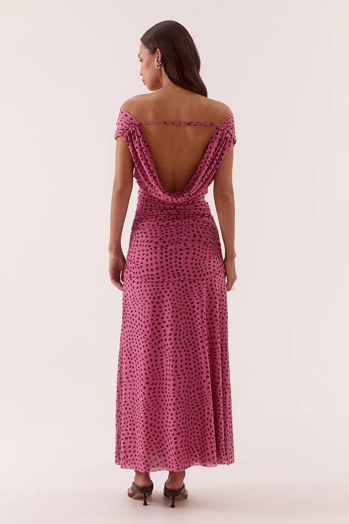 Woman wearing a pink polka dot dress with an open back on a white background